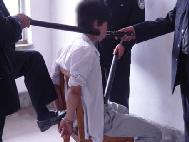 酷刑演示：恶警将法轮功学员反铐在椅子上，用脚踩在手铐上