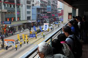 游行队伍走在弥敦道上，人行天桥上的民众也驻足观看。