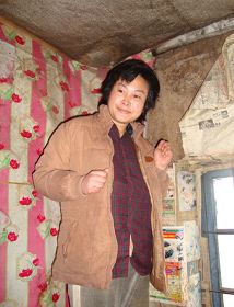 被迫害致疯的柳志梅，当有人试图接近，她就攥着双手躲向自家墙角（摄于二零一零年冬）