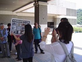 中国游客拿起相机，拍摄真相展板