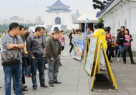 '中国大陆游客驻足在法轮功真相展板前认真观看。'