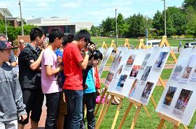 来自中国大陆的中学生争相阅读介绍法轮功和反迫害的真相展板，索要真相资料，并拍照录像。