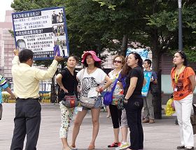 '退休宜兰教师李光辉正向中国游客讲真相（身着黄色衬衫拿展板）'