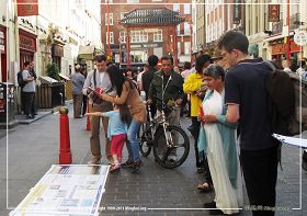 图2：英国法轮功学员在伦敦唐人街演示功法、讲真相并征集支持反迫害的签名，路人纷纷驻足了解真相。