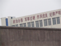 '潍坊市看守所（办公楼东楼），东楼上标着“政治合格 军事过硬……”的标语大字，显示看守所施行的是军事化管理、并把“政治”放在第一位、“政治”上向中共表态。'