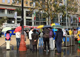图3：民众冒雨观看法轮功学员的反迫害游行集会。