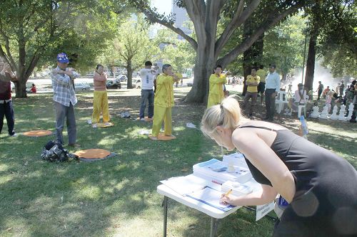 图4-6：在游园会上，法轮功学员设立了摊位，展示功法，并征集签名呼吁制止中共活摘法轮功学员人体器官的恶行。很多民众签名支持。