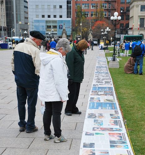 加拿大国会山前，路人阅读法轮功真相图片