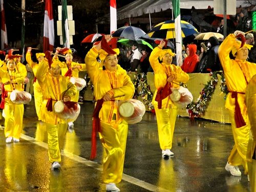 法轮功腰鼓队在夹道民众的热情欢迎中冒雨行进