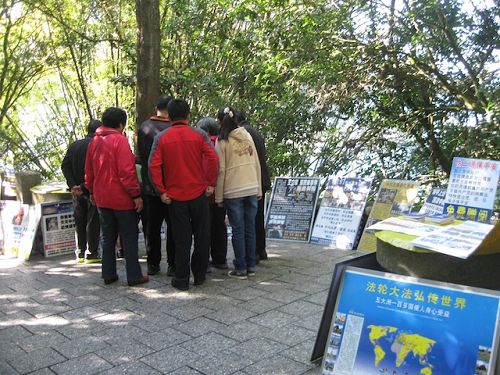 玄光寺步道上摆放很多真相展板，大陆游客正聚精会神的观看并讨论。