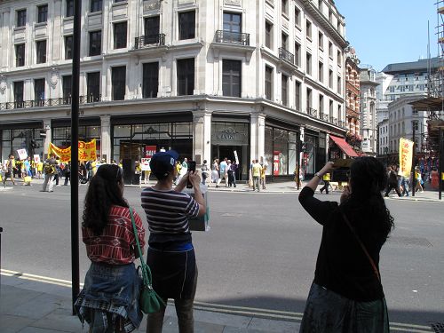 路过的华人看到法轮功学员的游行队伍，立即掏出相机或手机摄影和摄像