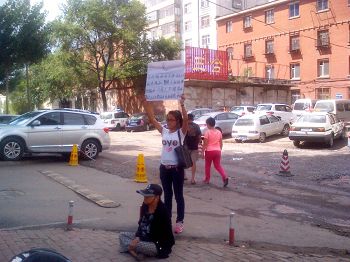 张海霞的女儿和近八十岁的母亲在香坊分局门前举牌抗议