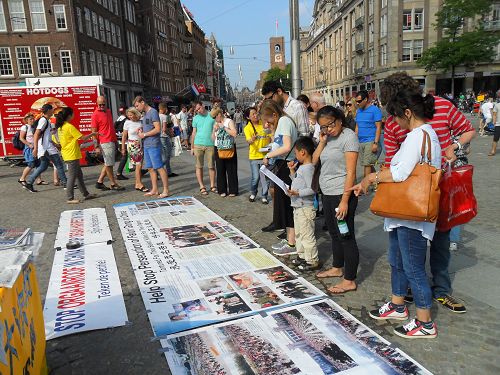 纪念和平反迫害十五周年，荷兰学员在阿姆斯特丹著名的达姆广场设立真相点，大批游人驻足阅读真相图片，了解真相。
