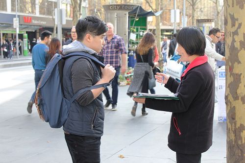 墨尔本大学的香港留学生小黄（左）认真的听学员讲真相