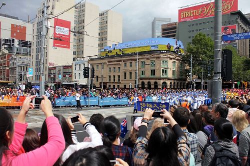 很多华人观众在夹道旁向正在走来的法轮功天国乐团拍照