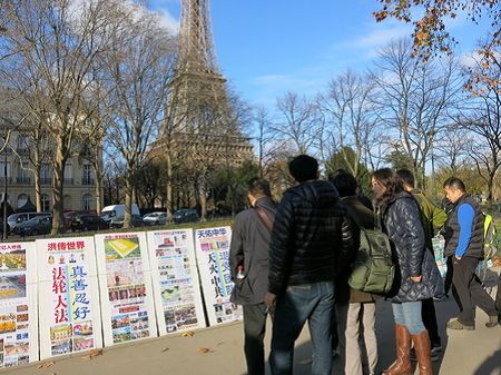 法国的法轮功学员在巴黎艾菲尔铁塔旁设立了真相点，成群结队的中国游客经过这里时，有许多人观看和阅读展板了解真相。