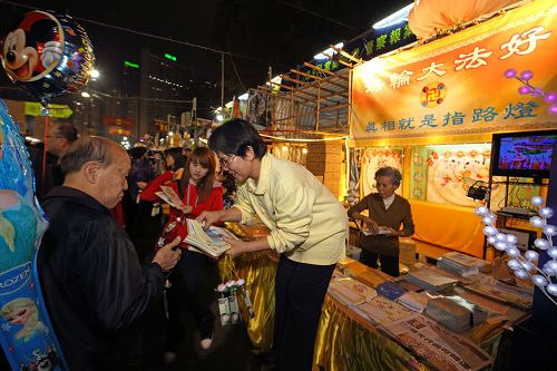 在年宵真相摊位前，法轮功学员向民众送上真相画刊及小莲花。