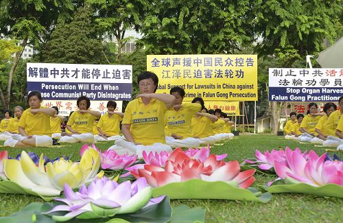 圖1－2：反迫害十六周年，新加坡法輪功學員在芳鄰公園舉辦活動，傳播法輪功真相，並將「訴江大潮」廣告民眾。
