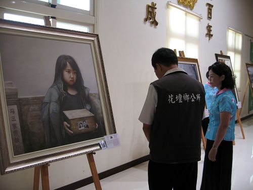 图5：花坛乡乡长李成济正在欣赏画作《孤儿泪》。