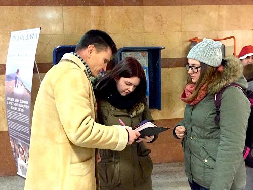 首都索菲亚的学员（左）在地铁口讲真相征签诉江