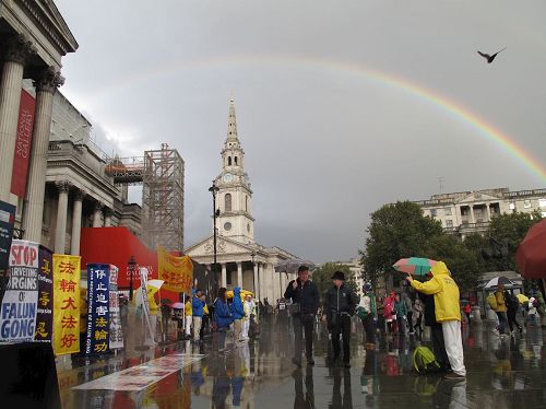 '图16：二零一六年十月一日下午，法轮功学员在特拉法加（Trafalgar Sqare）北平台举行集体炼功和讲真相活动时，天空中出现的彩虹'