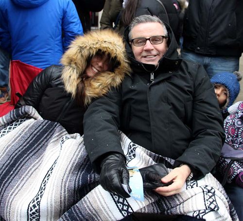 圖10：多倫多的Paul和妻子裹著被子在看遊行，他說：“天國樂團的演奏非常震撼人心，令我感慨的是這麼冷的天他們還能吹得這麼好聽，在給在寒冷中的我們帶來溫暖。”