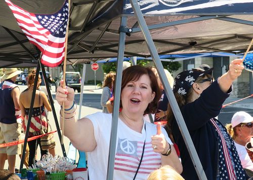 图11：红木城居民Tina Ford看到法轮功的队伍兴奋不已，不禁一只手竖起大拇指，另一只手摇着美国旗欢呼。