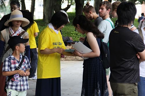 '图1-2：日本法轮功学员在广岛核爆七十一周年日来到广岛和平公园，向来自世界各地的民众揭露中共活摘法轮功学员器官的罪行，并征集签名声援诉江。'