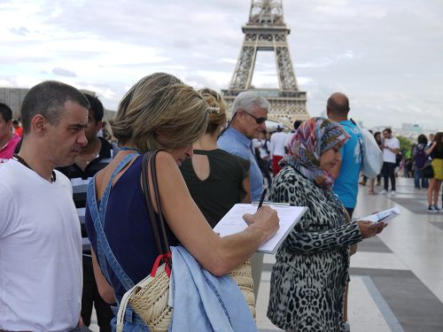 图1-4：二零一六年九月十一日下午，法轮功学员在巴黎铁塔下的人权广场，进行讲真相和征签活动。许多游客驻足了解真相，并签名支持法轮功学员反迫害。