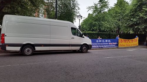 '图2：爱尔兰中使馆调遣车辆遮挡法轮功学员横幅，后被警方要求立即离开'