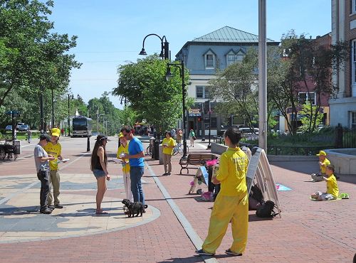 '图1：法轮功学员在佛蒙特州伯灵顿市街区给游人讲法轮功真相。'