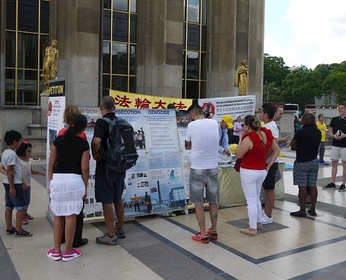 '图1～2：巴黎人权广场上，游人驻足了解法轮功真相'