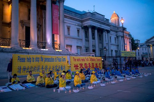 '图1～2：二零一七年七月二十三日，英国法轮功学员在伦敦特拉法加广场（又名鸽子广场）烛光守夜，呼吁世人携手制止中共迫害法轮功。'