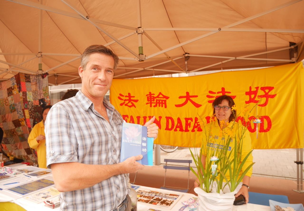 2017年8月13日,比利時依柯婁(Eeklo)舉辦世界市場(NOVA MONDO)節,法輪功展位受歡迎。圖為購得法輪功書籍而高興的 Jo Vanwontergem。(明慧網)