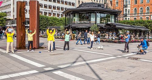 '图1：在瑞典文化节期间，法轮功学员在斯德哥尔摩的北城广场（Normalmstorget）设立真相点向民众介绍法轮大法的真相。图为学员们正在展示法轮功的第二套功法——法轮桩法。'