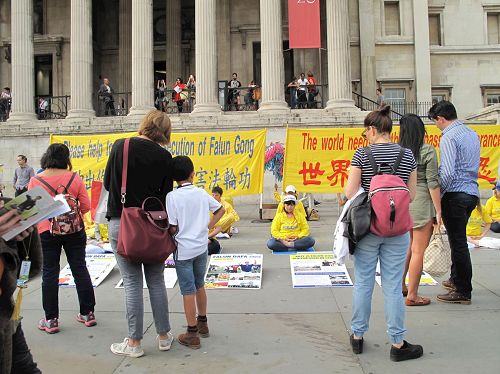 '图7～9：在伦敦特拉法加广场（Trafalgar Square），民众驻足认真观看集体炼功和真相展板'