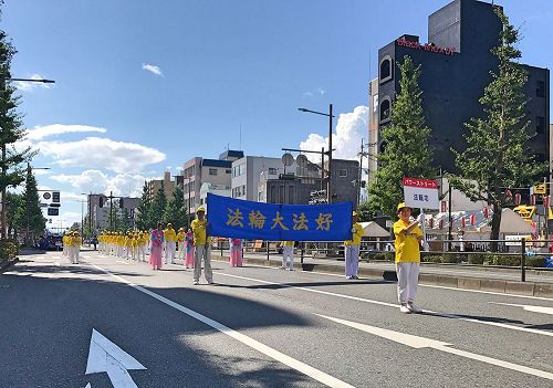 '图1～2：日本法轮功学员首次参加久留米市举办水之庆典游行，把法轮大法美好带给久留米市民。'