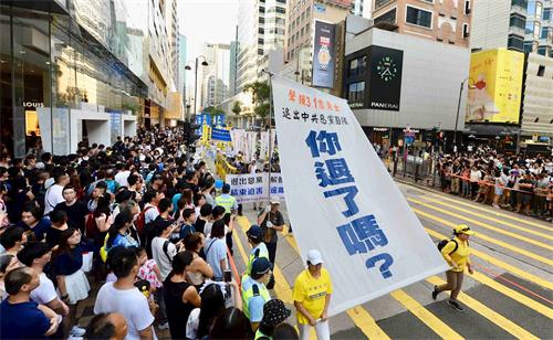 '图18：游行展示大型幡旗，呼吁中华儿女退出中共。'
