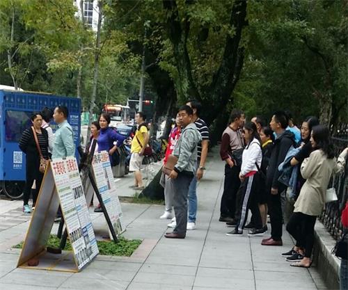 '图1～3：台湾法轮功学员在台北国父纪念馆前向过往游客传播法轮功的真相。不少大陆游客驻足观看真相展板。'