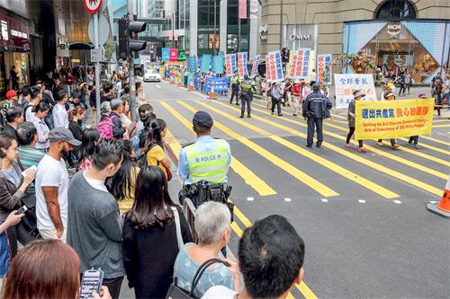 '图6～14：三月十八日下午二时，香港法轮功学员在香港市中心举行游行活动，庆祝并声援近三亿人退出中共党、团、队组织，吸引许多香港市民和大陆游客驻足观看。'