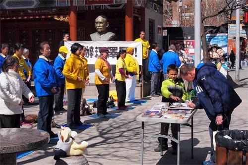 '图3：2018年4月21日，加拿大蒙特利尔的部份法轮功学员在唐人街中山公园举行集会和集体炼功，纪念四二五万人和平上访十九周年。现场民众了解真相后，在反迫害征签信上签字。'