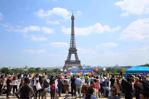 图3 ：五月二十日，法国法轮功学员在法国巴黎人权广场庆祝法轮大法日，吸引过往的游客和法国民众驻足观看、拍照、摄像。