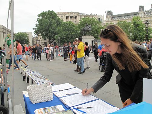 图7：在伦敦读硕士研究生的匈牙利女孩马里亚纳·菲力维（Mariana Filive ）在特拉法加广场签名支持法轮功反迫害。