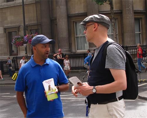 图9：二零一八年六月十二日，在伦敦圣马丁广场，从比利时安特卫普来伦敦旅游的保罗（Paul，右）与遇到的法轮功学员交谈。