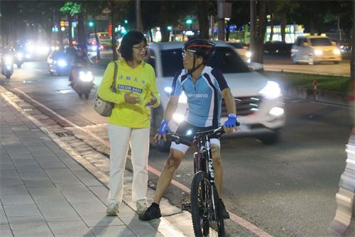 '图4：法轮功学员正在向一位停下脚步关注的自行车骑士解说活动意义。'