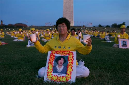 '图5：王春荣女士面前摆放着孙莲霞的照片，她双手举起蜡烛，悼念曾经相识的这位同修。'