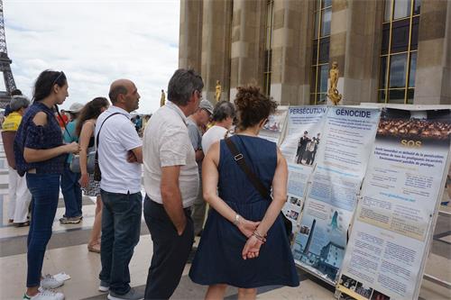'图1～2：巴黎人权广场上，过往游客认真阅读法轮功真相展板'