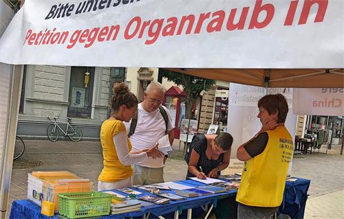 '图1～4：二零一八年七月七日，德国法轮功学员在西南边陲Lörrach市举办了传播法轮功真相信息日。不少民众驻足了解真相，签名支持制止活摘。'