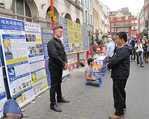 '图6：二零一八年八月十一日，在伦敦法轮功学员杰克帮助下，一位来自立陶宛的年轻商界人士（左）第一次尝试法轮功功法，惊呼神奇'