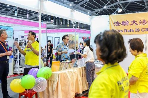 '图1～3：二零一九年十月十一日至十三日，法轮功学员在新加坡博览中心（Singapore Expo）举办的健康保健展上设立展位，向人们介绍法轮功，并免费教功。'